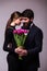 Portrait of young couple in love with bouquet of lila tulips posing dressed in classic clothes on grey backround.