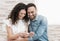 Portrait of a young couple reading hugging pregnancy test result - married couple is happy to expect a baby - warm flare on