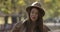 Portrait of young cute European girl in elegant hat taking off sunglasses and shaking her long brown hair. Charming