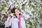 Portrait of young dreaming woman in white blooming cherry branches in spring outdoor