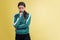 Portrait of young emotional girl in green tracksuit posing isolated on yellow studio background in neon light. Emotions