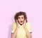 Portrait of a young emotional woman in yellow dress, an open mouth and an expression of fear on her face. On light pink background