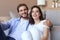 Portrait young family of happy husband and wife sitting in sofa cuddle looking at camera posing