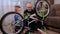 Portrait of a young father and his son repair a broken bicycle together at home.