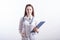 Portrait of a young female doctor in a white uniform with a folder in hands in the studio on a white background.