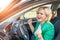 Portrait of a young female driver at the wheel. Happy cheerful blonde with blue eyes sings at the wheel of a car