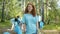 Portrait of young female eco activist smiling in forest while team collecting trash