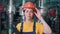 Portrait of a young female engineer standing in a production room and smiling. Moving away from the face. Modern