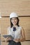 Portrait of young female industrial worker using tablet PC with wooden planks in background