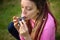 Portrait of young female shaman in pink knitted sweater playing on ceramic ocarina in the forest during autumn or spring