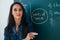 Portrait of young female teacher against chalkboard in class