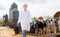 Portrait of young female veterinarian taking care of calves on dairy farm, walking with buckets near outdoor stall