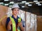 Portrait of young female warehouse worker standing in warehouse holding digital tablet and showing thumbs up, Smiling woman in