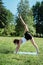 Portrait of young fitness trainer practicing pilates exercise in quit summer park, morning time