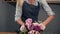 Portrait of a young flower shop assistant tying a bunch of flowers lying on her table with the ribbon. Slowmotion shot