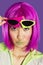 Portrait of young funky woman in pink wig puckering lips over purple background