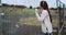 Portrait of young girl dressed in pink vest near metallic fence. Girl listening music in headphones and thinking while