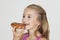 Portrait of young girl eating donut against gray background