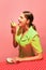 Portrait of young girl eating oyster like an ice cream isolated over red background