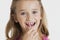 Portrait of young girl flossing teeth against gray background