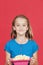 Portrait of young girl holding popcorn container against red background