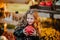 Portrait of young girl holding red pumpkin at the open market place. Autumn background