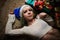 Portrait of young girl lies under Christmas tree with presents