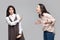 Portrait of young girl looking at camera and showing stop or ignore to another girl who screaming at her. conflict between two