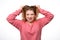 Portrait of young girl in panic shouting and grabbing her head in fear or frustration. Studio shot, white background