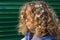 Portrait of a young girl with small white flowers in her hair, cropped shot. Teenage girl with curly hair outdoors.