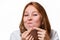 Portrait of a young girl squeezing out a pimple on her chin. White background. The concept of acne and skin problems