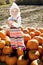 Portrait of a young girl standing on pumpkin