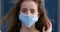 Portrait of young girl teenager curly beautiful woman putting on medical surgical protective mask on female face