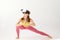 Portrait with young girl wearing sportswear and VR glasses doing yoga exercise over white background. Virtual sport