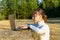 Portrait of a young girl working at a laptop that stands on a haystack in a field