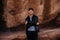 Portrait of Young Good Looking Casual Traveling Handsome Man Smiling Near Ancient Desert Red Rocks in Jacket Outside