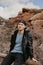 Portrait of Young Good Looking Casual Traveling Handsome Man Smiling Near Ancient Desert Red Rocks in Jacket Outside