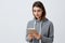 Portrait of young good-looking caucasian student girl with dark long hair in casual gray hoodie holding digital tablet