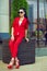 Portrait of young gorgeous dark-haired businesswoman in sunglasses and bright red suit sitting at the office building