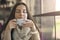 Portrait of young gorgeous female drinking cup of coffee and enjoying her leisure time alone