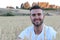 Portrait of a young gorgeous natural man sitting in a wheat field