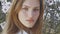 Portrait of a young green-eyed woman with blond hair against the background of a flowering almond tree