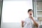 Portrait of young handsome Asian male speaker publicly speaking on stage to group of audience with white board behind.