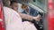 Portrait of young handsome car dealer looking in car with blurred wealthy couple sitting in salon. Professional salesman