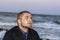 Portrait of young handsome man against background of sea in the evening. Look up, romantic mood