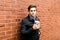 Portrait of young handsome man with cup of coffee of brick wall