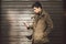 Portrait of young handsome Turkish male model of Mediterranean race brunet in leather coat using hand phone of