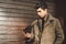 Portrait of young handsome Turkish male model of Mediterranean race brunet in leather coat using hand phone of