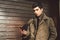 Portrait of young handsome Turkish male model of Mediterranean race brunet in leather coat using hand phone of