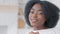 Portrait of young happy african girl with curly hair looking at camera shoot finger pistol gesture, close-up of female